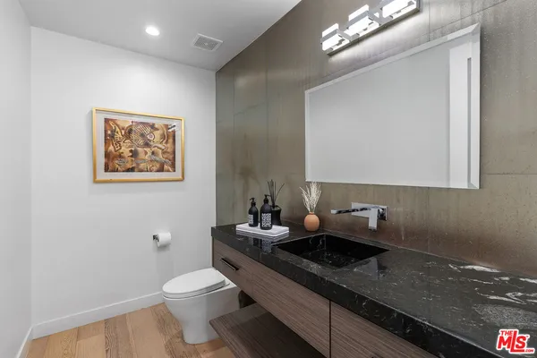 a bathroom with a granite countertop double vanity sink a mirror and a toilet