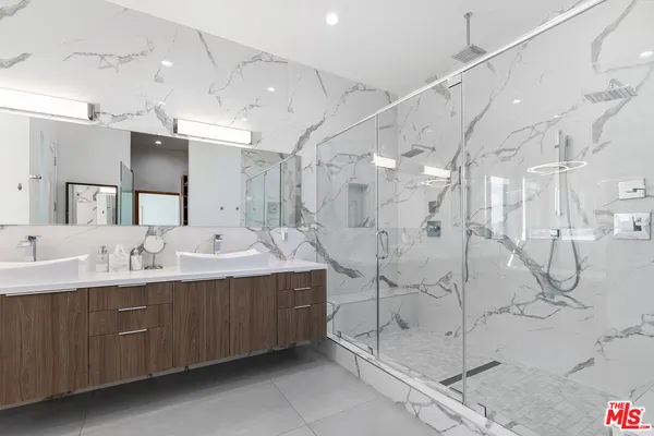 a bathroom with a double vanity sink mirror and shower