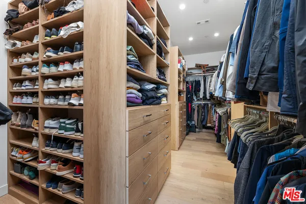 a view of walk in closet with clothes and shoes