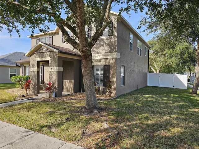 a view of a house with small yard and large tree