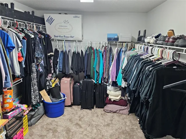 a view of walk in closet with clothes and shoes