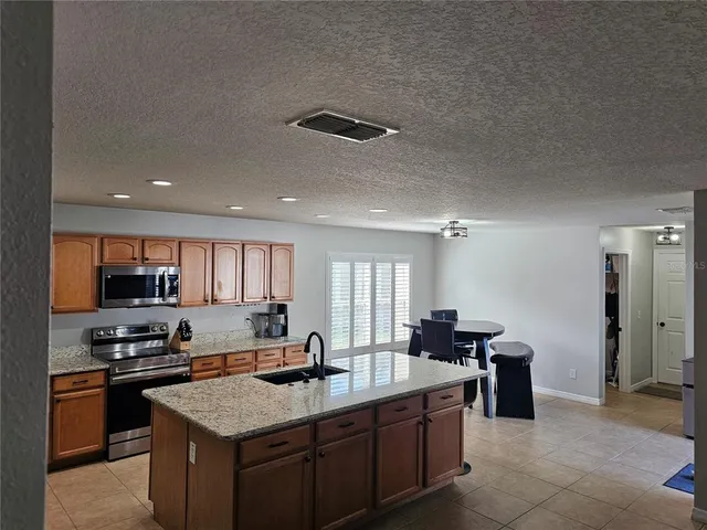 a kitchen with stainless steel appliances granite countertop a sink a stove and a refrigerator