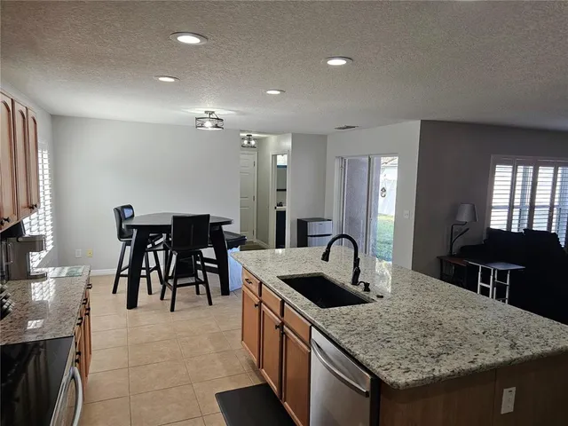 a kitchen island with granite countertop a table and chairs in it