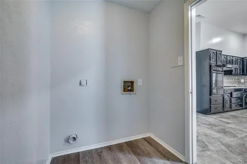 a view of a hallway with wooden floor and a bathroom