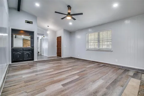 an empty room with wooden floor and a ceiling fan
