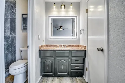 a bathroom with a granite countertop toilet a sink and a mirror