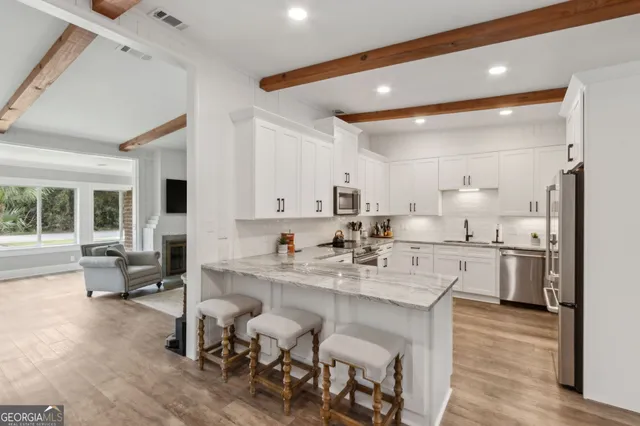 a dining room with wooden floor a chandelier a wooden table and chairs