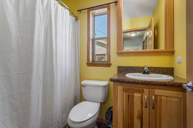 a bathroom with a granite countertop sink toilet and mirror