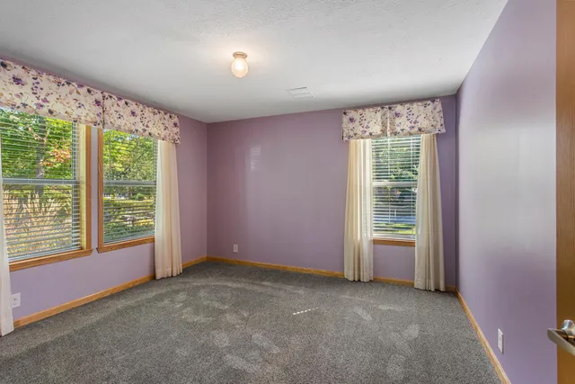 an empty room with a fireplace and large windows