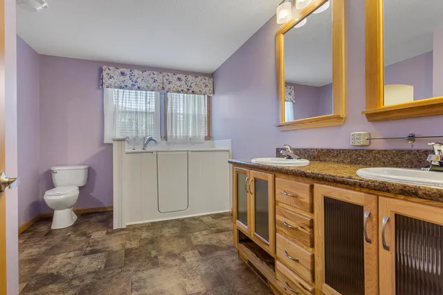 a bathroom with a granite countertop toilet sink and mirror