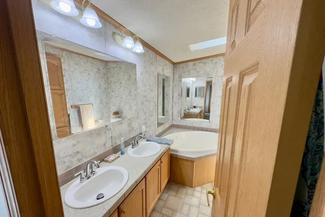 a bathroom with a double vanity sink a mirror a bathtub and shower