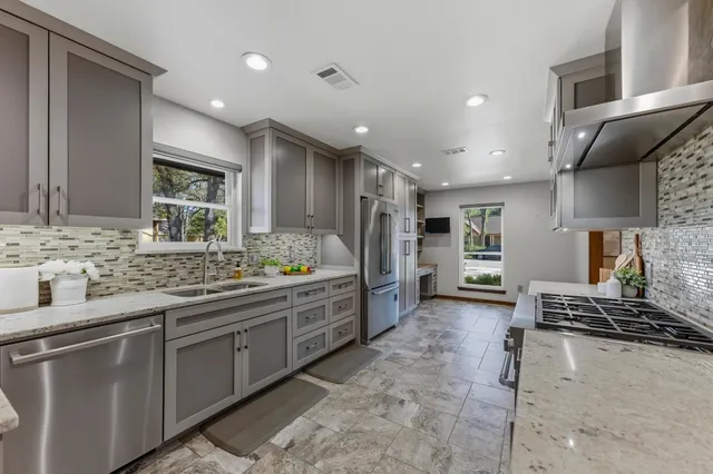 a large kitchen with stainless steel appliances kitchen island granite countertop a sink and cabinets