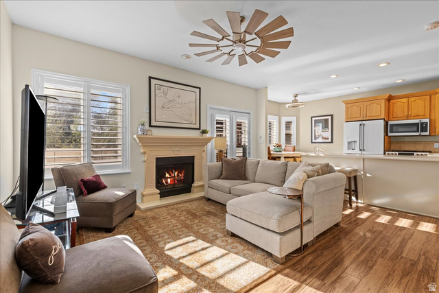 7824 South Sequoia Tree Lane Sandy, UT 84094 - Photo 5 of 43 Living room with light wood-type flooring, recessed lighting, a warm lit fireplace, plenty of natural light, and a ceiling fan