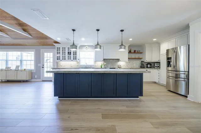 a large kitchen with kitchen island wooden floors wooden cabinets a center island and stainless steel appliances