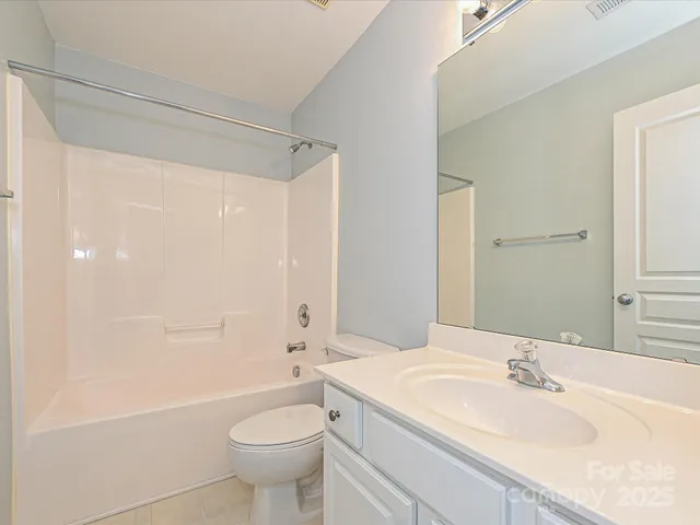 a bathroom with a granite countertop sink a toilet a mirror and shower