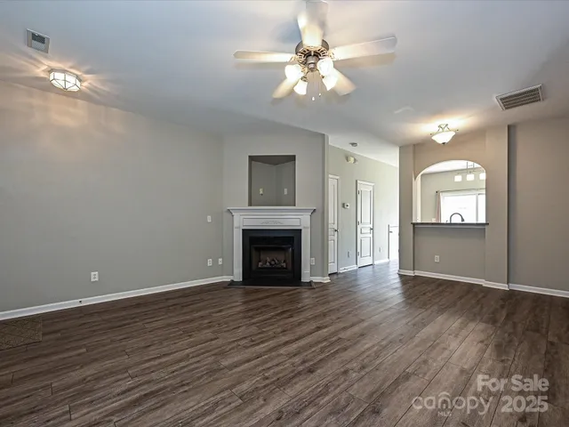 a view of an empty room with wooden floor and a fireplace