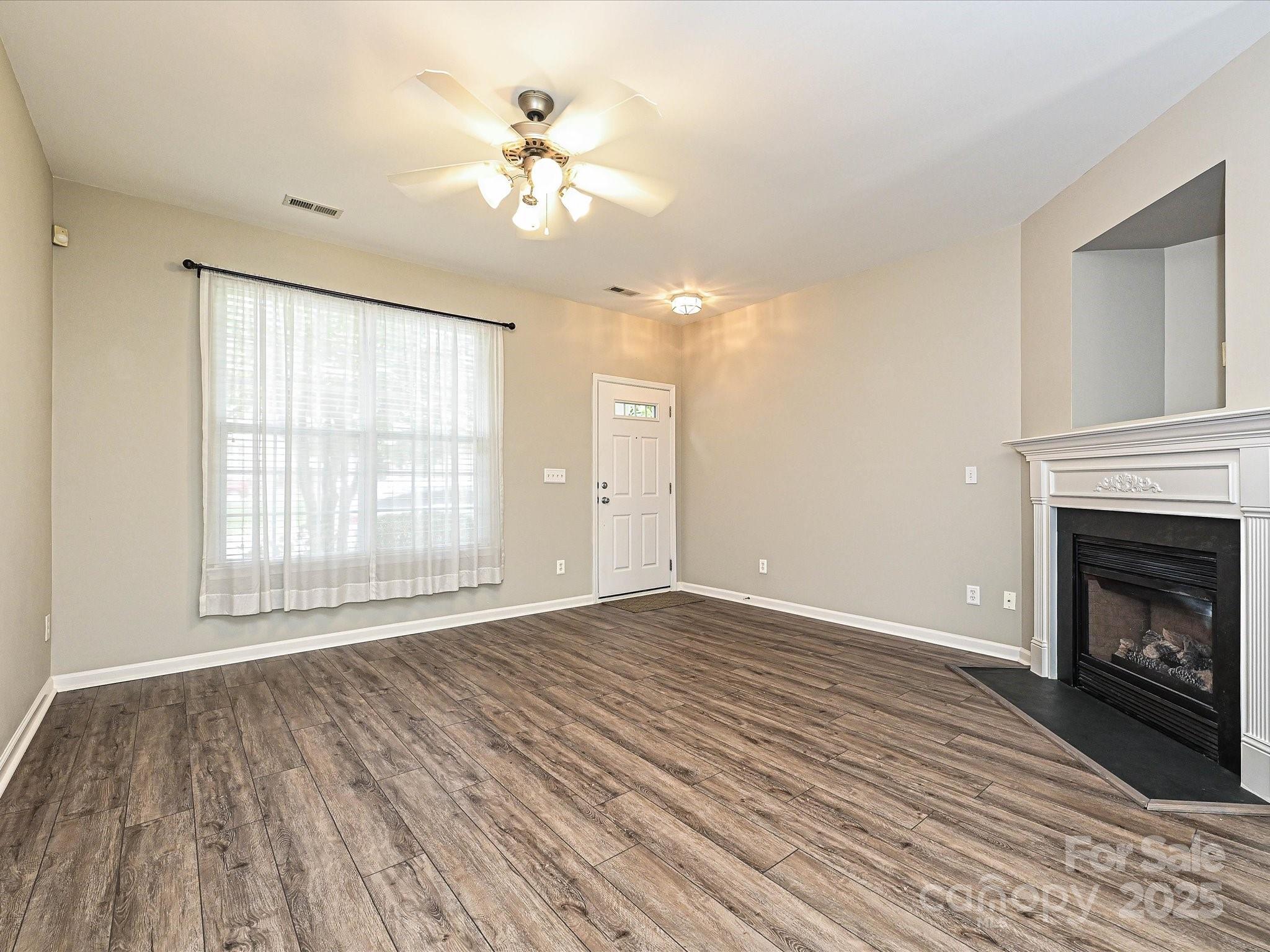 1115 Drummond Lane Matthews, NC 28104 - Photo 7 of 24 a view of an empty room with wooden floor fireplace and a window