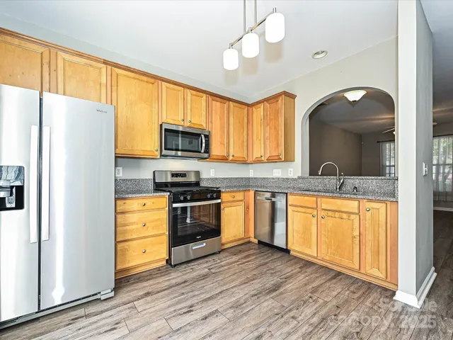 a kitchen with stainless steel appliances granite countertop a refrigerator a stove top oven a sink and cabinets