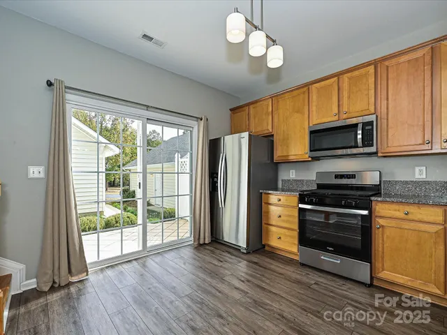 a kitchen with stainless steel appliances granite countertop a stove top oven a refrigerator a kitchen island a sink and a microwave