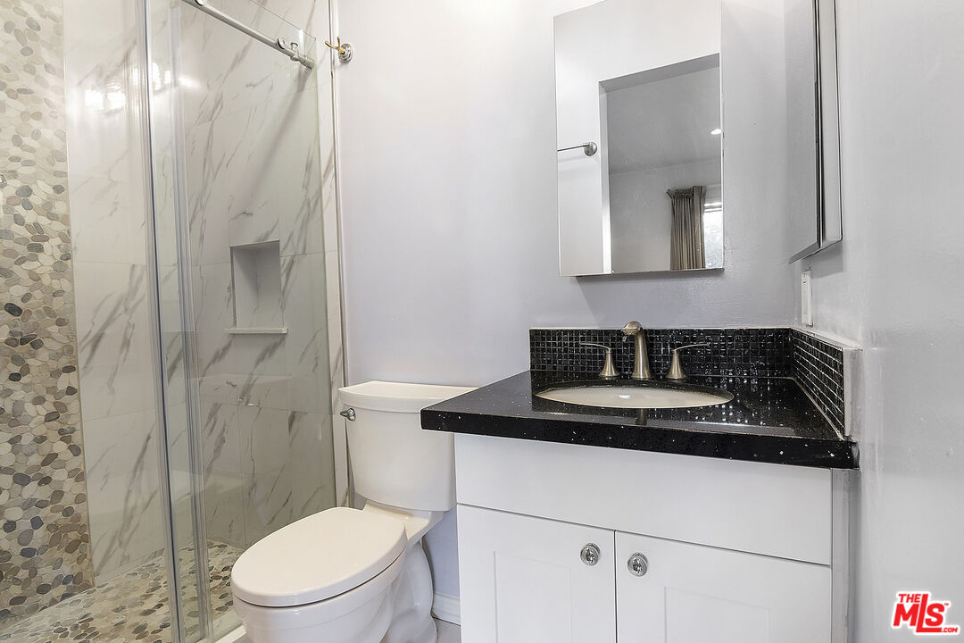 923 17th Street, Unit 3 Santa Monica, CA 90403 - Photo 17 of 22 a bathroom with a granite countertop sink toilet a mirror and shower