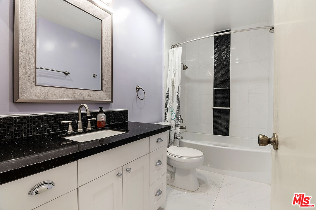 923 17th Street, Unit 3 Santa Monica, CA 90403 - Photo 19 of 22 a bathroom with a granite countertop sink a toilet a mirror and shower