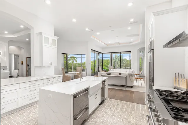 a large white kitchen with a large window and stainless steel appliances