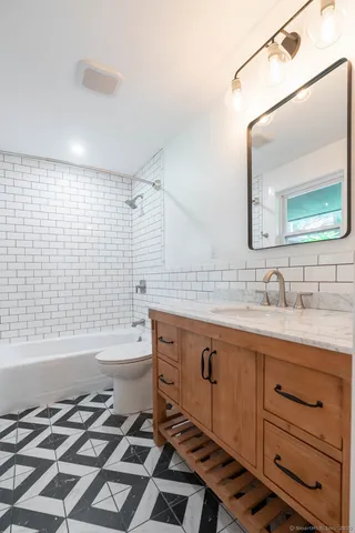 a bathroom with a granite countertop sink toilet mirror and bathtub