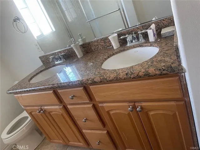 a bathroom with a granite countertop sink a toilet and mirror