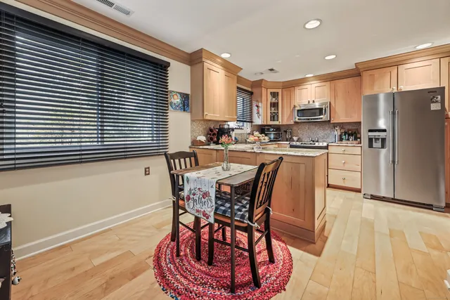 a dining room with stainless steel appliances kitchen island granite countertop a table chairs and a refrigerator