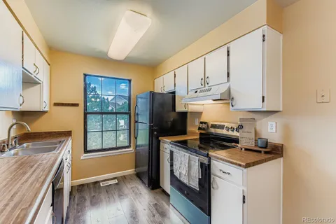 a kitchen with stainless steel appliances granite countertop a stove a sink and a refrigerator with wooden floors