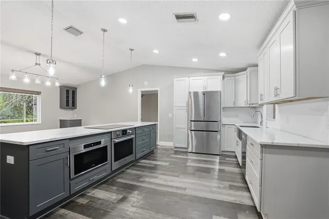 a kitchen with stainless steel appliances granite countertop a sink and white cabinets with wooden floor