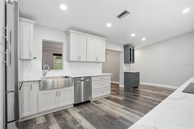 a living room with stainless steel appliances wooden floor and a cabinet
