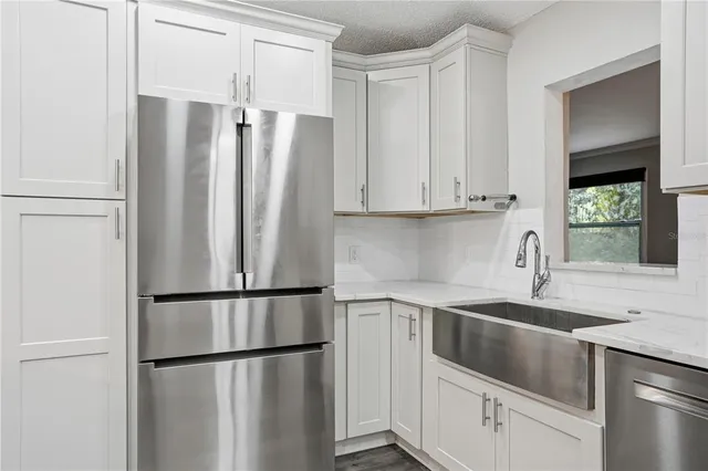 a large kitchen with kitchen island a sink stainless steel appliances and a chandelier