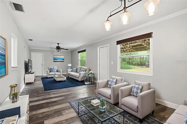 a view of an empty room with window and chandelier fan