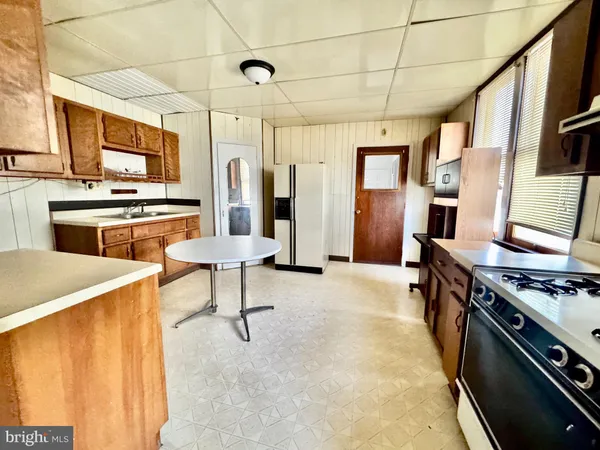 a kitchen with stainless steel appliances granite countertop a stove top oven a sink dishwasher a dining table and chairs with wooden floor