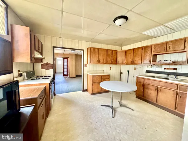 a kitchen with stainless steel appliances kitchen island granite countertop a table chairs sink and cabinets