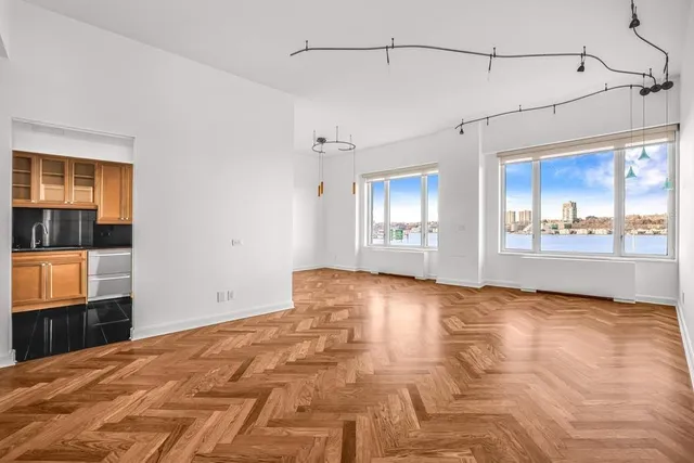a view of a livingroom with wooden floor and a kitchen