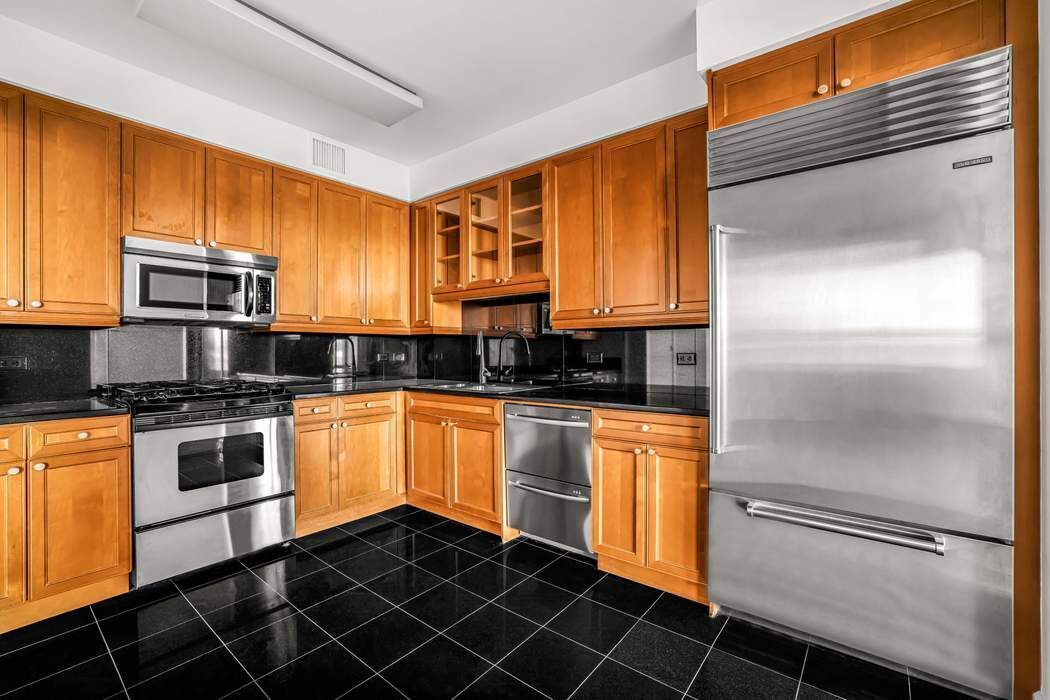 220 Riverside Boulevard, Unit 5L Manhattan, NY 10069 - Photo 4 of 16 a kitchen with granite countertop stainless steel appliances and wooden cabinets