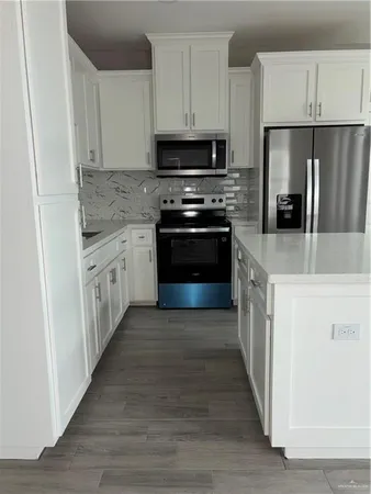 a kitchen with stainless steel appliances granite countertop a refrigerator a stove a sink and a microwave