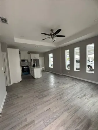 a view of an empty room with a window and wooden floor