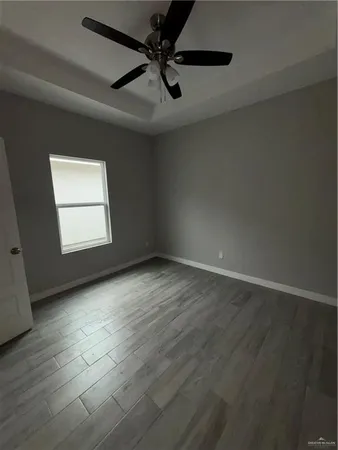 an empty room with wooden floor ceiling fan and windows