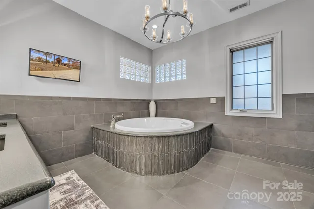 a bathroom with a tub a window and a potted plant