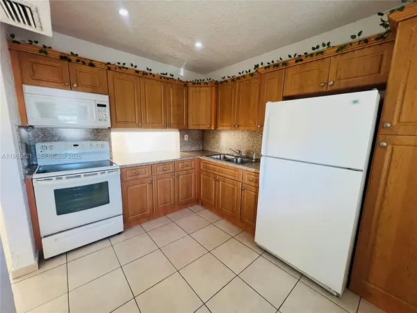 a kitchen with granite countertop a refrigerator sink stove and cabinets