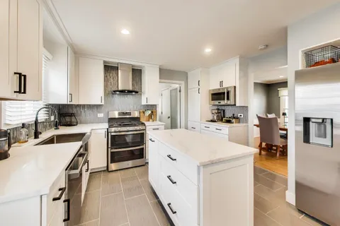 a kitchen with white cabinets and stainless steel appliances