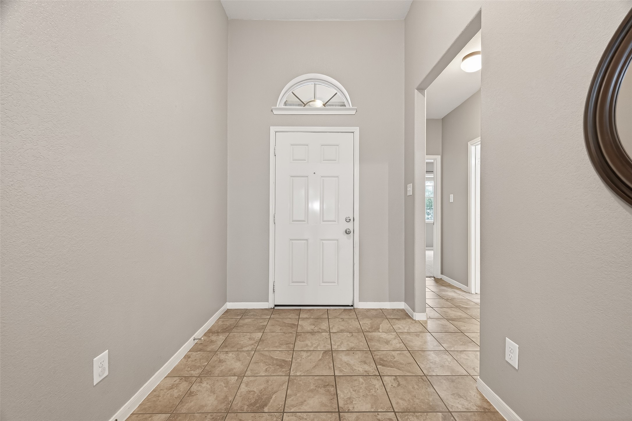 9110 Cavalier Lane Rosenberg, TX 77469 - Photo 4 of 30 The inside entryway with neutral walls and tiled flooring, leads to a bright interior. The door features an elegant arched window, enhancing natural light.