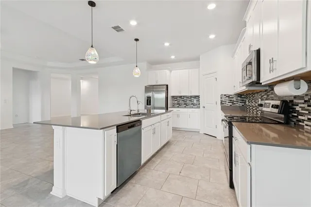a large kitchen with stainless steel appliances kitchen island granite countertop a sink a stove and a refrigerator