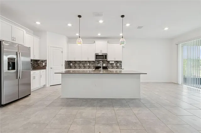 a view of kitchen with stainless steel appliances granite countertop a stove a sink a refrigerator and white cabinets