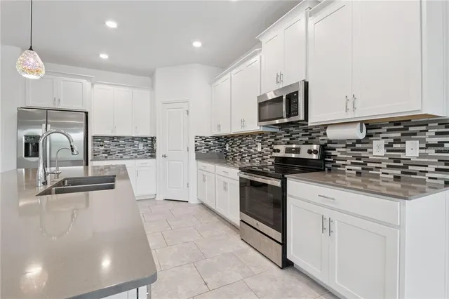 a kitchen with granite countertop a sink stainless steel appliances and white cabinets
