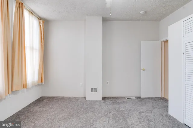 an empty room with closet and a chandelier fan