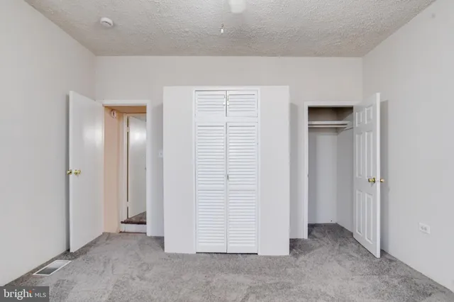 an empty room with a chandelier fan and windows